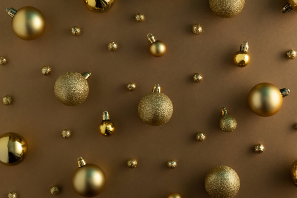 Golden Christmas baubles on illuminating background. Aesthetic Christmas and New Year ornament concept. Monochromatic retro composition. - Photo, Image