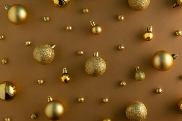 Golden Christmas baubles on illuminating background. Aesthetic Christmas and New Year ornament concept. Monochromatic retro composition. - Foto, imagen