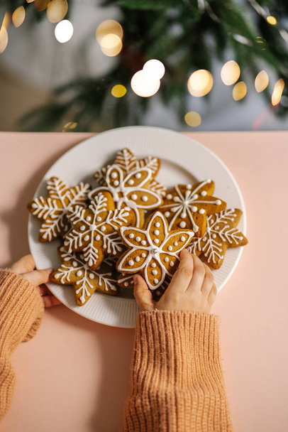 Ginger Christmas cookies in childrens hands on the background of the Christmas tree. - Φωτογραφία, εικόνα
