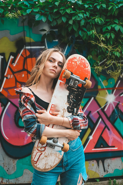 Frau auf einem Skateboard auf farbenfroher Street Art. Skater-Mädchen auf einem Longboard. Coole Skateboarderin bei Sonnenuntergang. Unbekümmerte Skaterinnen 20er Jahre genießen Freiheit Jugendstil Hobby - Foto, Bild