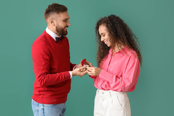 Young man proposing to his girlfriend on color background - Fotografie, Obrázek