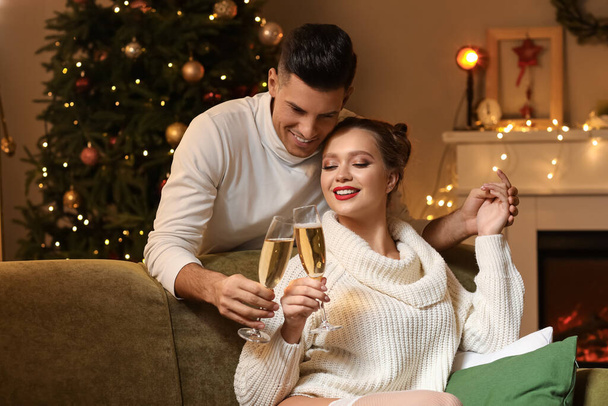 Ευτυχισμένο νεαρό ζευγάρι πίνοντας σαμπάνια ενώ έχουν ρομαντική ημερομηνία την παραμονή των Χριστουγέννων - Φωτογραφία, εικόνα