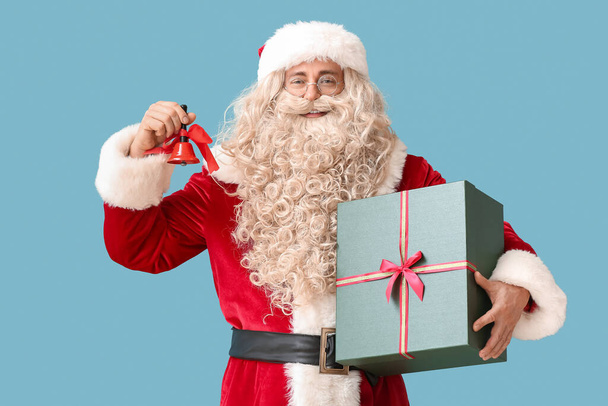 Weihnachtsmann mit Weihnachtsglocke und Geschenk auf blauem Hintergrund - Foto, Bild