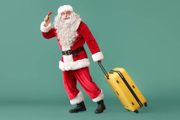 Άγιος Βασίλης με χριστουγεννιάτικο κουδούνι και βαλίτσα σε πράσινο φόντο - Φωτογραφία, εικόνα