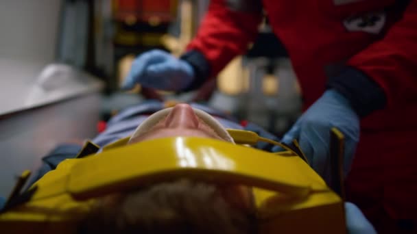 Ambulancia paramédica en guantes que examinan al paciente en camillas en un coche de ambulancia - Imágenes, Vídeo