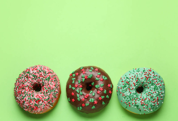 Tasty Christmas donuts on green background - Photo, Image
