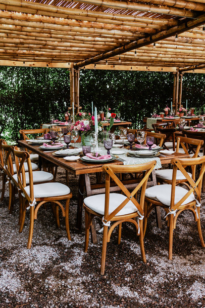Terasa se stoly s květinami a talíři na stole zdobené pro svatební hostinu v Latinské Americe - Fotografie, Obrázek