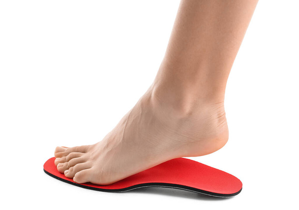 Weiblicher Fuß und rote orthopädische Einlegesohle auf weißem Hintergrund - Foto, Bild