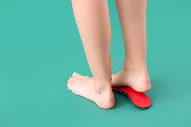 Female feet and red orthopedic insole on green background - Foto, Imagem