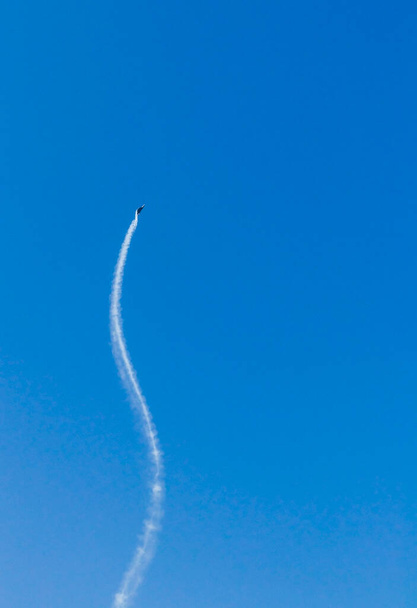 Militair vliegtuig dat stunts uitvoert in een heldere blauwe lucht - Foto, afbeelding