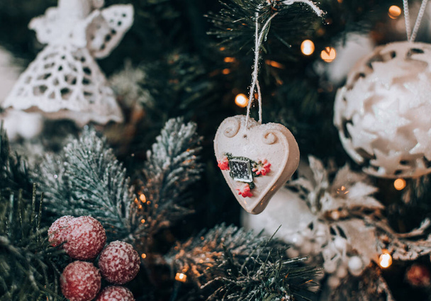 Heart shaped ornament hanging on a decorated christmas tree at home. - Zdjęcie, obraz
