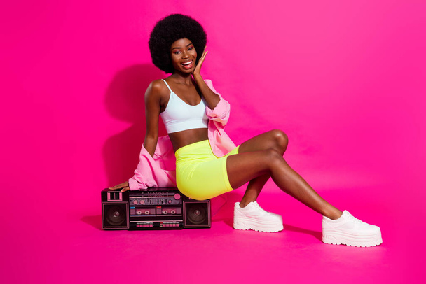Photo of funny impressed dark skin lady wear casual shirt sitting boom box isolated pink color background - Фото, зображення