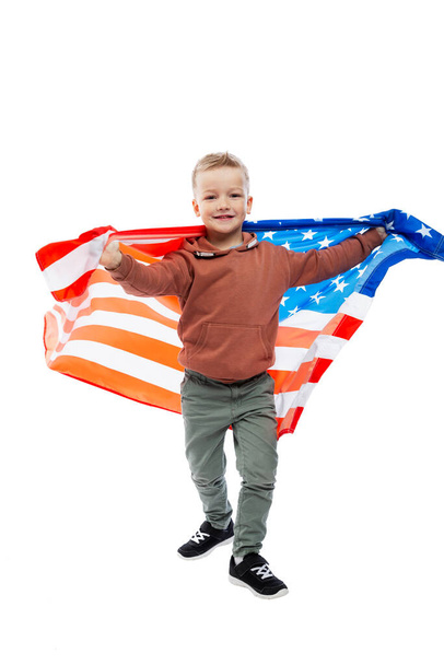 A joyful boy holding a waving American flag in his hands. Independence Day and patriotism. Isolated on white background. Vertical. - Foto, immagini