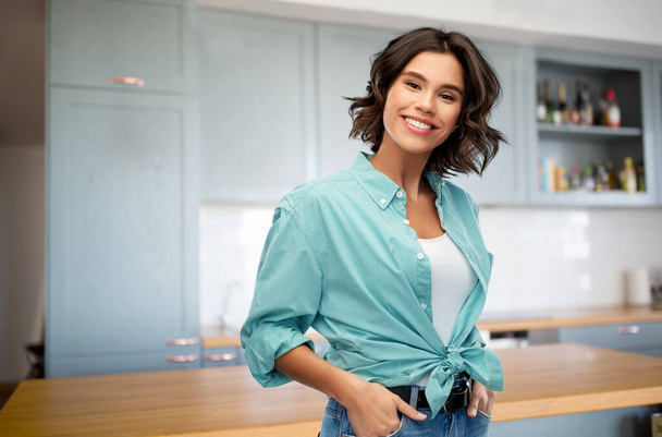 smiling young woman in turquoise shirt on kitchen - Фото, изображение