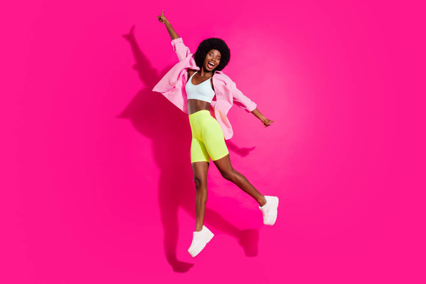 Full length profile side photo of young excited african girl happy positive smile jump up isolated over pink color background - 写真・画像