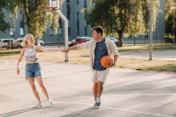 happy couple with ball on basketball playground - Foto, imagen