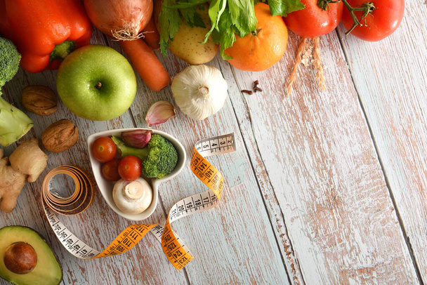 Balanced menu concept with fruits and vegetables on wooden table and heart-shaped bowl and measuring tape. Top view. Horizontal composition. - Photo, Image