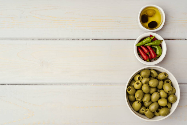 Olives in a bowl on wooden background, top view - 写真・画像