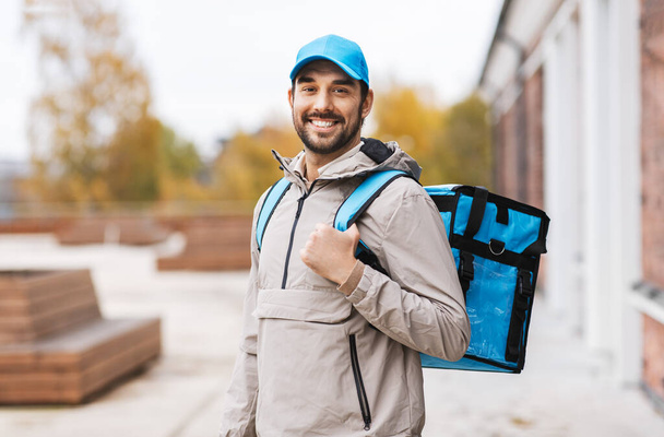 happy delivery man with thermal bag in city - Foto, imagen