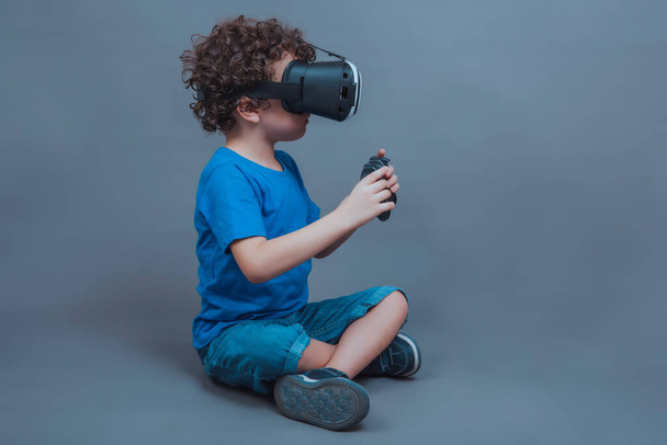 Kaukázusi fiú ül VR szemüveg és játék vezérlő - Fotó, kép