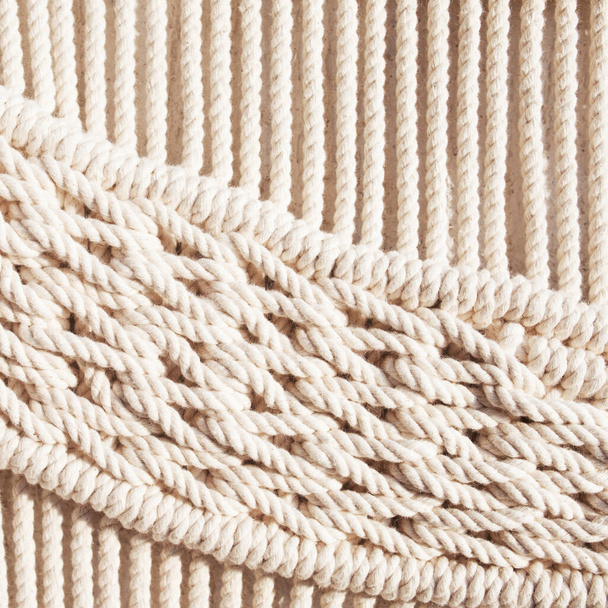 Close-up of hand made macrame texture pattern. ECO friendly modern knitting DIY natural decoration concept  in the interior.  Handmade macrame 100% cotton. Female hobby. - Zdjęcie, obraz