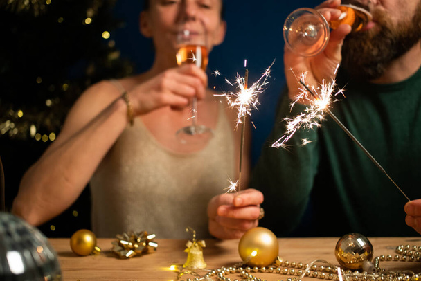 happy couple holding sparkles and champagne glasses New Year party - Фото, изображение