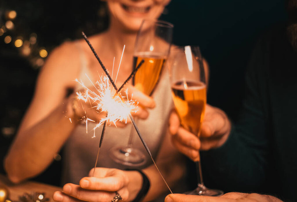 felice coppia che tiene scintille e bicchieri di champagne festa di Capodanno - Foto, immagini