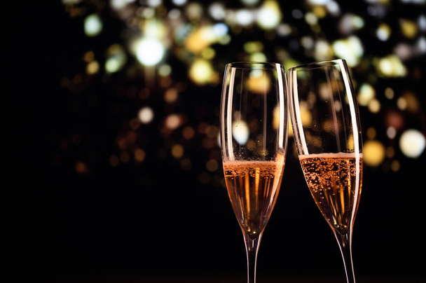 İki şampanya kadehi ve neşeli ışık yeni yılınız kutlu olsun. - Fotoğraf, Görsel
