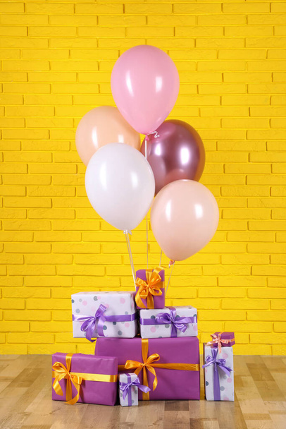 Molte scatole regalo e palloncini vicino al muro di mattoni gialli - Foto, immagini