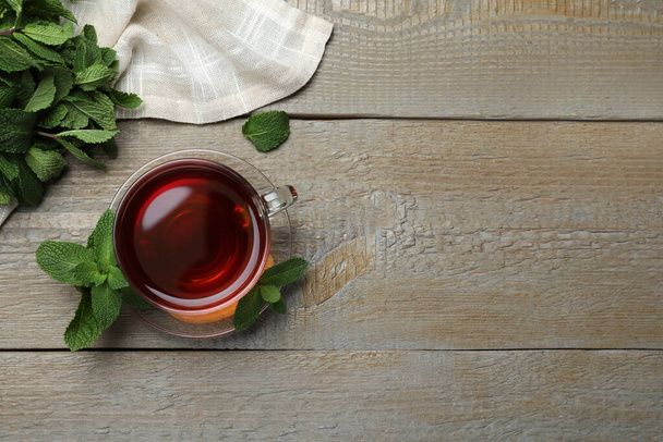 Cup of hot aromatic tea with mint on wooden table, flat lay. Space for text - Fotoğraf, Görsel
