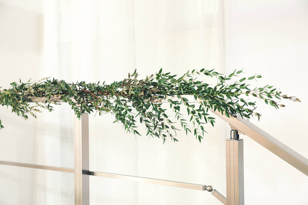 Beautiful garland made of eucalyptus branches on handrail indoors - Foto, immagini