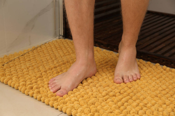 Man standing on soft mat near shower stall in bathroom, closeup - Zdjęcie, obraz