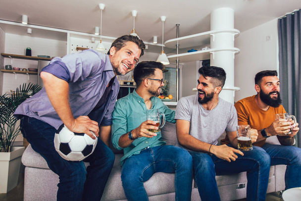 Very excited friends having fun by watching football match at home, indoors. Friendship, leasure,sport, rest, home party concept - Foto, Imagem