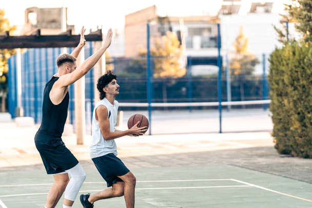 Zwei kaukasische Freunde spielen im Sommer Basketball auf einem Außenplatz - Foto, Bild