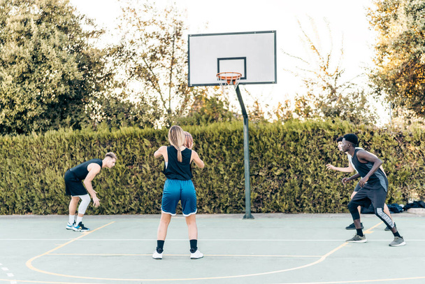 Женщина собирается забить три очка во время игры в баскетбол на открытом воздухе - Фото, изображение
