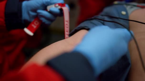 Torniquete paramédico en el brazo del paciente. Médico preparando al hombre para análisis de sangre - Metraje, vídeo
