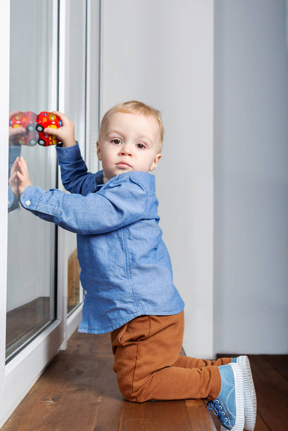 Child playing dangerously on a window sill. - Фото, зображення