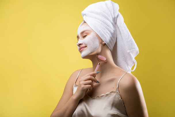 Menina com uma máscara cosmética em seu rosto em uma toalha branca. - Foto, Imagem