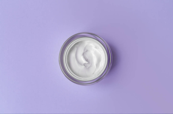 White cream jar on violet blue background close-up. Beauty cosmetics presentation. Top view - Photo, Image