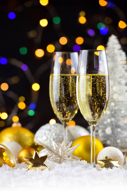 Два бокала шампанского и рождественские украшения на снегу на темном праздничном фоне. С Новым годом. - Фото, изображение