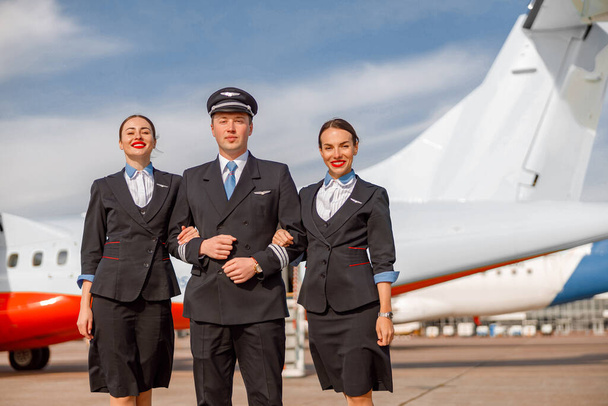Aircraft pilot and flight attendants standing outdoors at airfield - Photo, Image