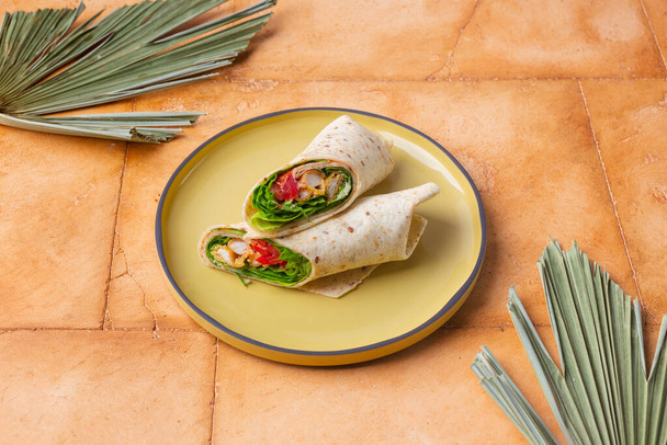 Pair of fresh wrap sandwiches with chicken and vegetables on yellow plate - Valokuva, kuva