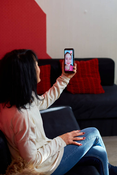 Happy grandmother having videocall on cellphone online talk with granddaughter, distantly communication, mature woman sits on couch at home, using smartphone, technology concept - Foto, Imagem