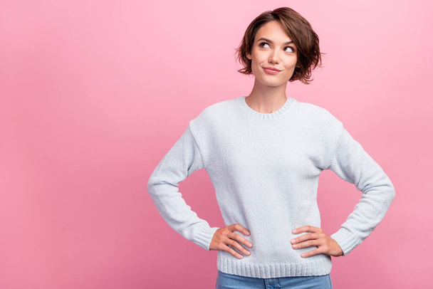 Photo of dreamy young minded woman look empty space hands waist smile isolated on pink color background - Foto, Imagem