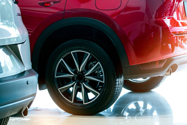Closeup wheel of red car parked in showroom. Wheel and tire of new car. Car dealership business concept. Auto leasing and car insurance. Automotive industry. New red shiny auto for sale in showroom. - Fotoğraf, Görsel