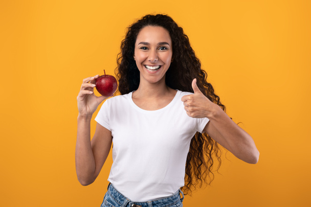 Portrait of Smiling Latin Lady Holding Apple Showing Like - Photo, Image