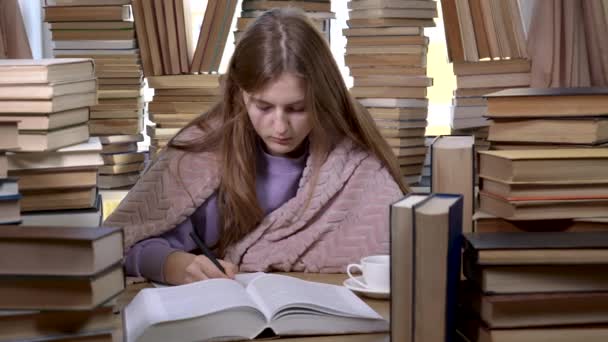 Ένα κορίτσι διαβάζει ένα βιβλίο στη βιβλιοθήκη. - Πλάνα, βίντεο
