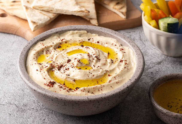 Close-up of chickpea hummus seasoned with olive oil in a gray bowl, healthy vegan food. - Fotoğraf, Görsel