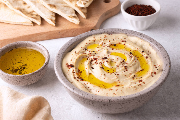 Chickpea hummus seasoned with olive oil and paprika on white background, vegetable dip and salad dressing. - Foto, immagini