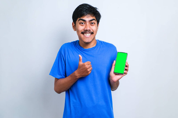 Asiatique Guy sourire à la recherche de camée Affichage Smartphone écran vide recommander l'application, fond blanc - Photo, image